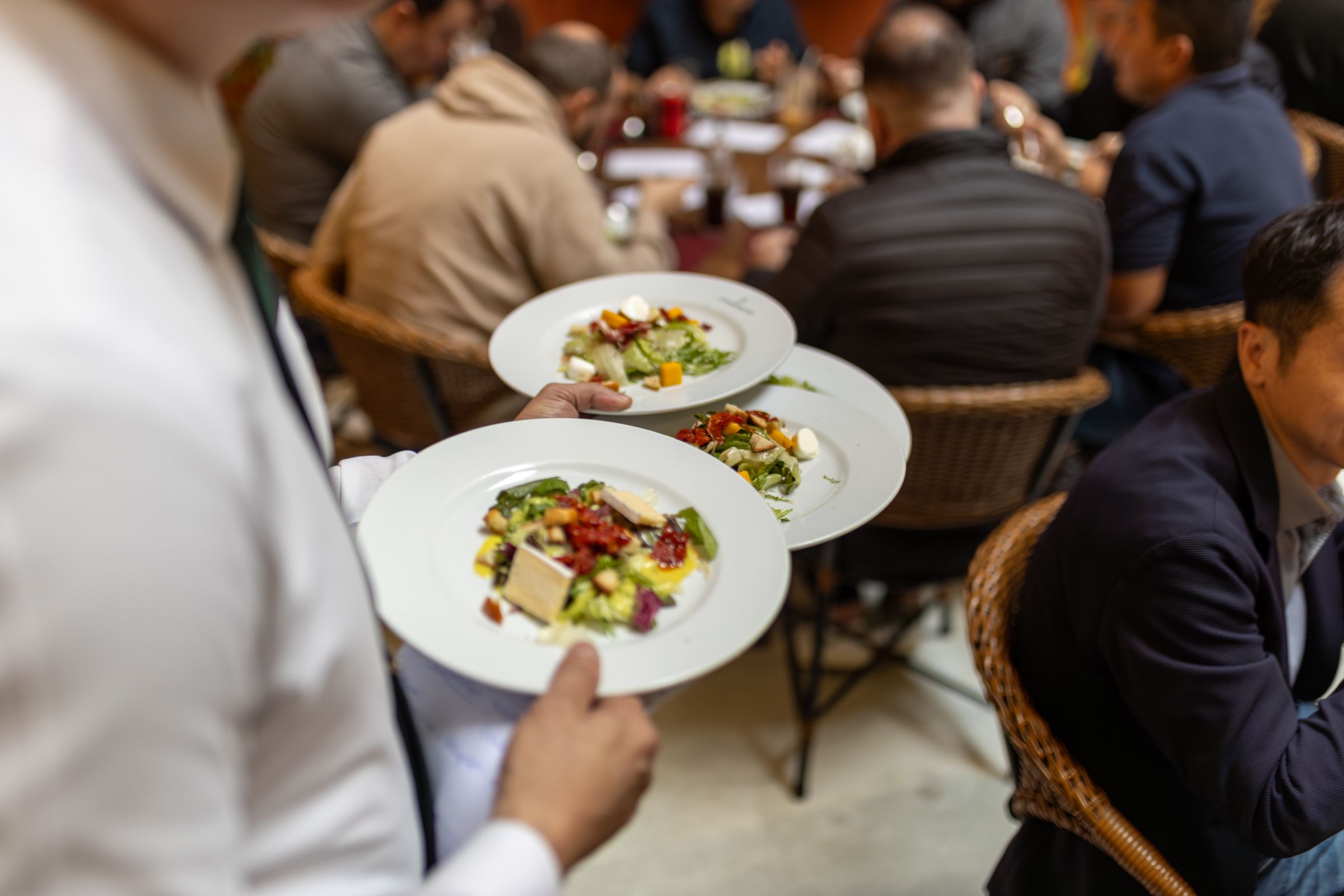 A waiter carrying plated meals through a busy service