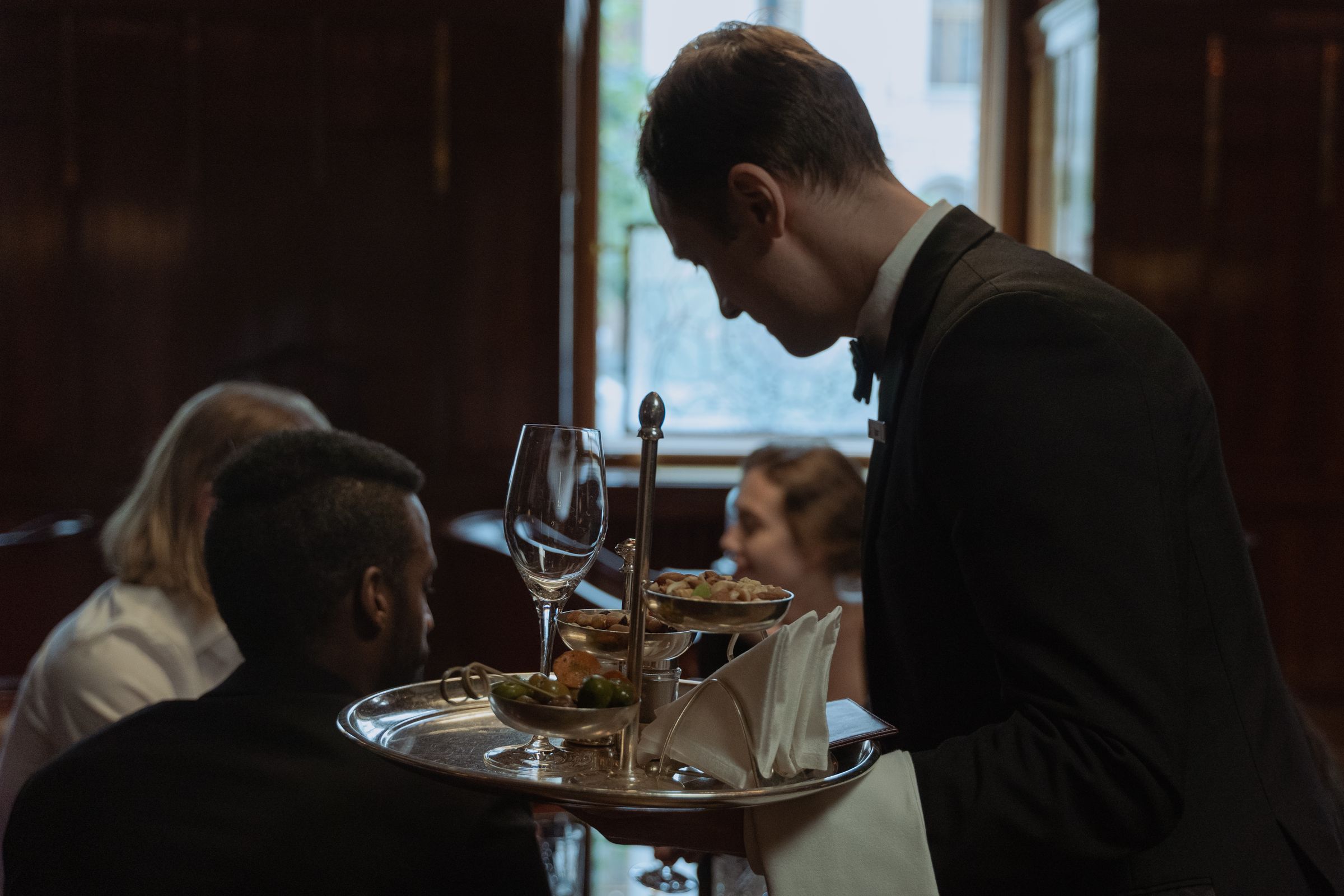 A waiter carrying drinks and canapes through a restaurant